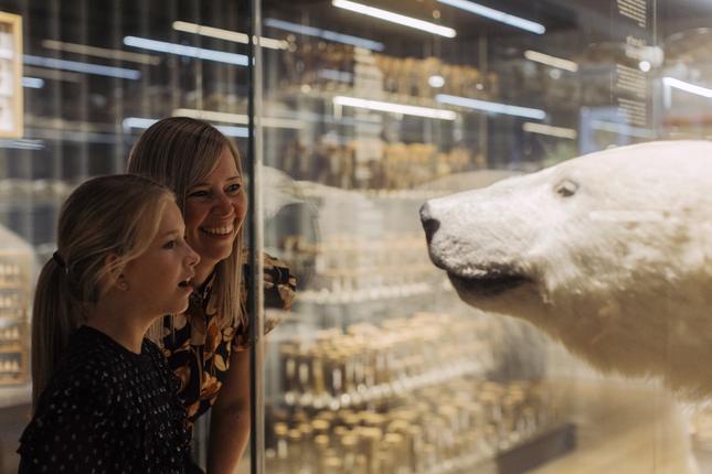 Mor og datter foran isbjørn i montre